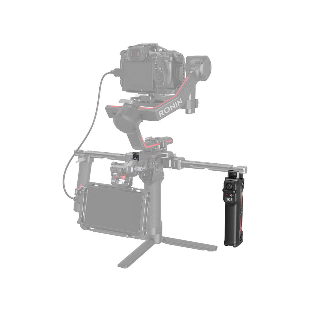 SmallRig_Handgrip_with_Wireless_Control_For_DJI_RS_Series_3949_004 Ammattimainen kamera-asetelma, jossa on SmallRig 3949 Handgrip with Wireless Control for DJI RS Series, RONIN-kardaanivakaaja, kiinnitetty kamera, ulkoinen näyttö ja joystick-kahva jalustalla valkoista taustaa vasten.