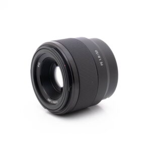 Sony 50mm f18-2 Sony FE 50mm f/1.8 - Käytetty -objektiivi, jonka kyljessä lukee "FE 1.8/50", on kuvattu valkoisella pohjalla, ja objektiivin etulasi ja objektiivin tynnyri on kuvakulmassa.