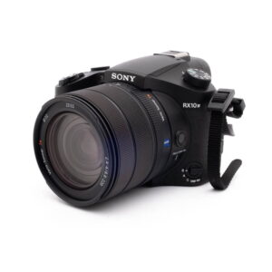 Sony RX10 IV-4 Sony RX10 IV - Käytetty -digitaalikamera näkyy vinossa valkoisella taustalla, ja siinä on suuri Zeiss-objektiivi ja oikealla puolella näkyvä kamerahihna.