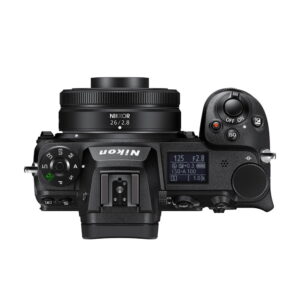 nikkor_z_26mm_01 Nikon-kameran yläkuva, jossa on Nikkor Z 26mm f/2.8 -objektiivi, jossa on säätöpyörät, painikkeet ja kameran asetuksia näyttävä näyttö.