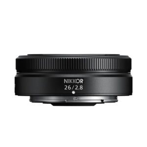 nikkor_z_26mm_03 Pienikokoinen musta Nikon Nikkor Z 26mm f/2.8 -objektiivi näkyy valkoista taustaa vasten, ja siinä on kuvioitu tarkennusrengas ja "26/2.8"-merkintä etupuolella.