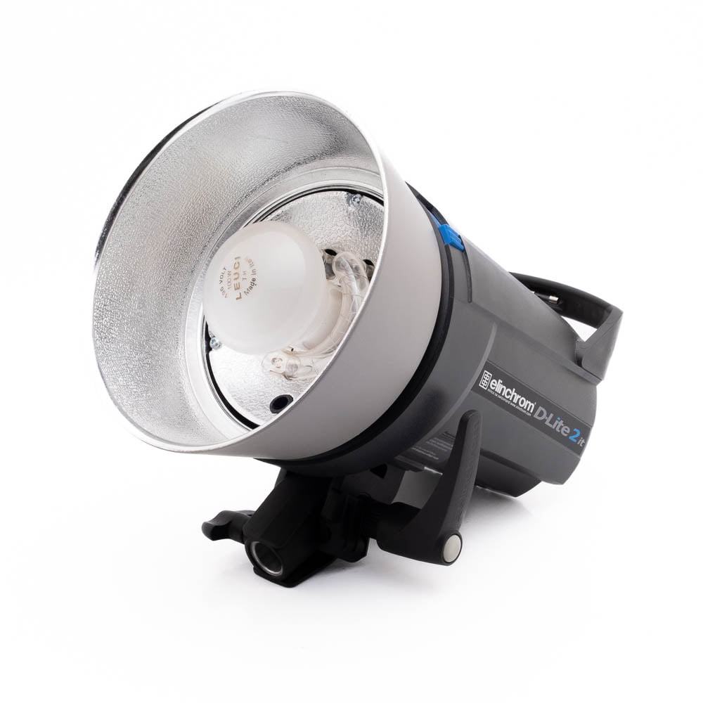 Elinchrom D-Lite 2 it-1 Elinchrom D-Lite 2 it - Käytetty studiostroboskooppivalaisin, jossa on hopeinen heijastin ja valotettu lamppu, on asetettu kyljelleen valkoista taustaa vasten.