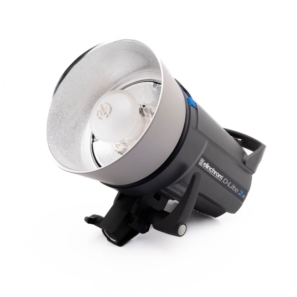 Elinchrom D-Lite 2 it-4 Elinchrom D-Lite 2 it - Käytetty studiostrobovalo, jossa on hopeinen heijastin ja Elinchromin tuotemerkki, on kuvassa kyljellään valkoista taustaa vasten.