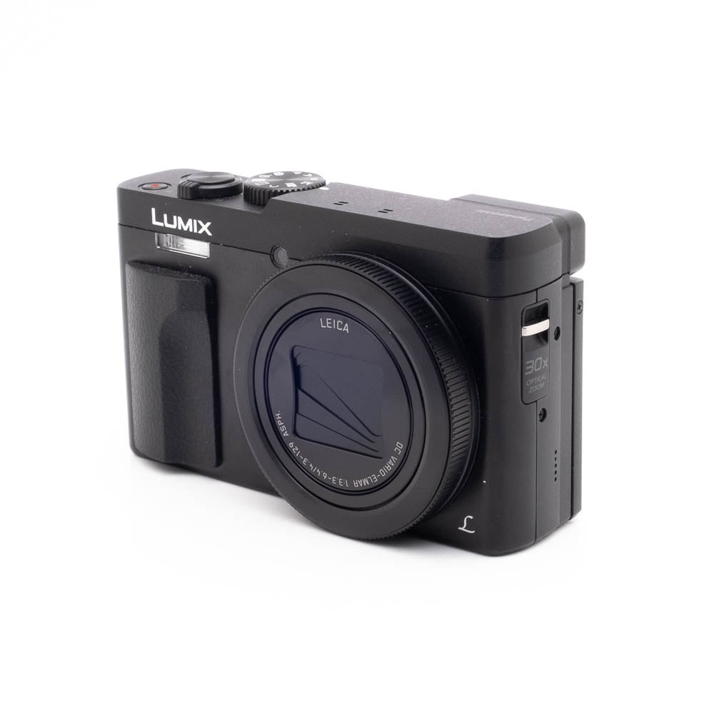 Panasonic DC-TZ90 7657-5 Musta Panasonic Lumix DC-TZ90 - Käytetty -digitaalikamera näkyy valkoisella taustalla, ja sen Leica-objektiivi, ergonominen kahva ja sivusäätimet korostuvat.