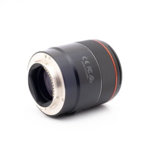 Samyang 75mm f18 FE Canon-1 Panasonic Lumix DC-TZ90 - Käytetty on kuvattu valkoisella pohjalla, ja siinä on musta runko, hopeinen metallirunko ja punainen korostusrengas. Sen kyljessä näkyvät sertifiointimerkinnät ja Made in Korea -teksti.