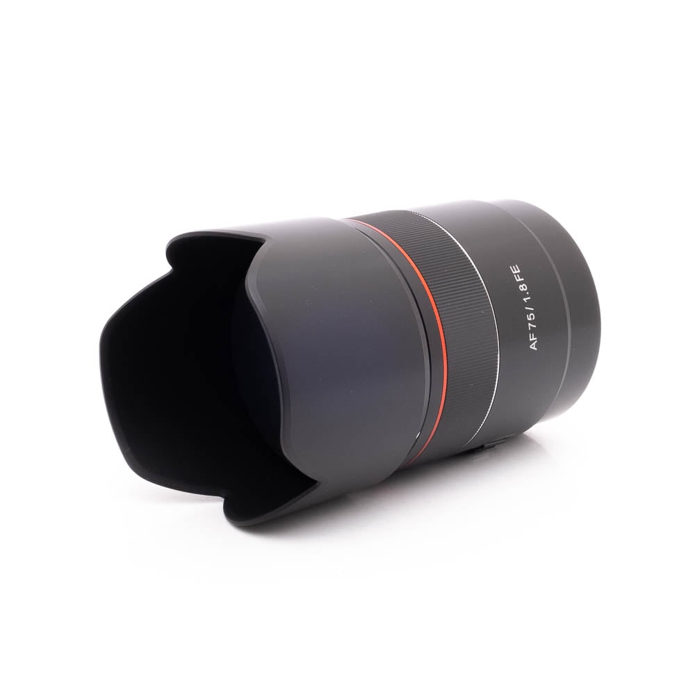 Samyang 75mm f18 FE Canon-3 Panasonic Lumix DC-TZ90 - Käytetty kameran objektiivi, jossa on vastavalosuoja ja erottuvat merkinnät, istuu valkoisella taustalla.