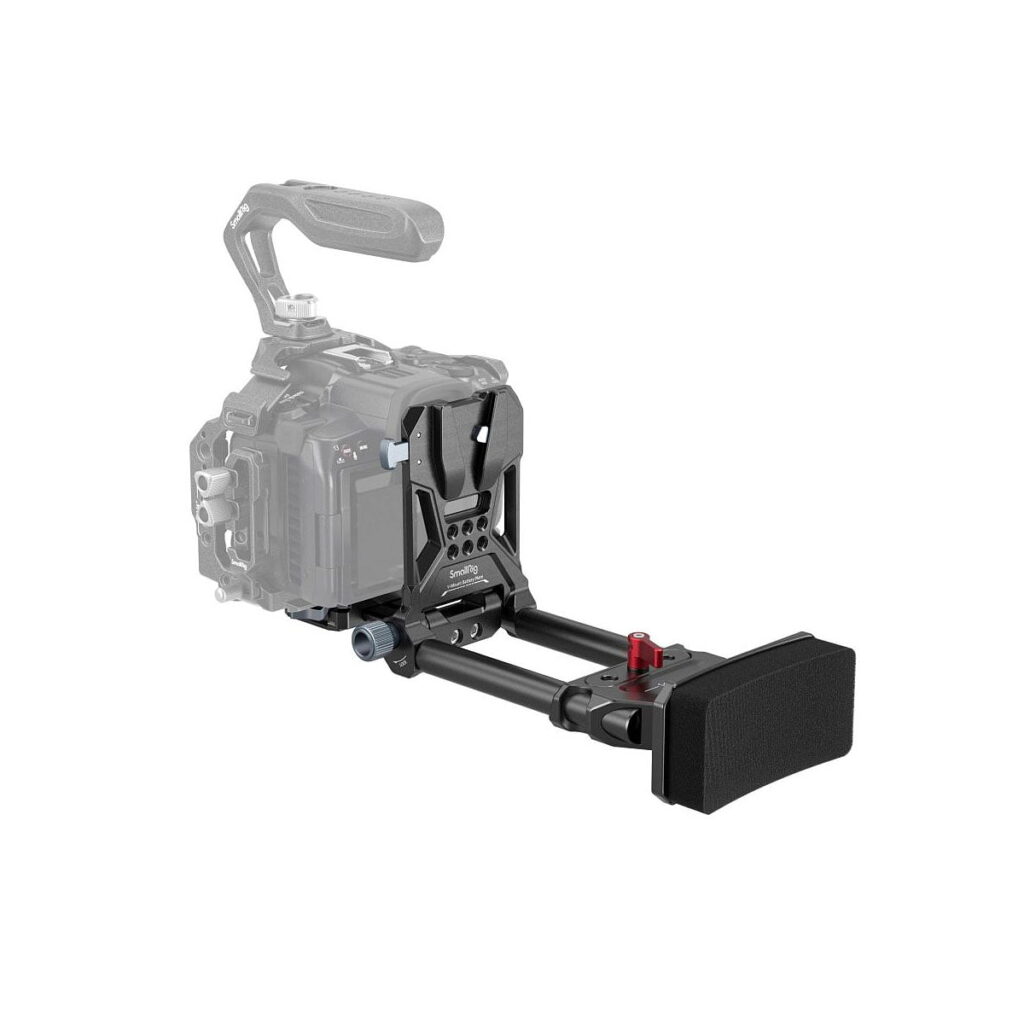 SmallRig_4063_001 SmallRig 4063 Advanced Compact V-Mount -akkujen kiinnitysjärjestelmässä on kaksi tankoa, säädettävä olkatuki, yläkahva ja useita kiinnityspisteitä lisävarusteille; kuvassa kiinnitettynä osittain läpinäkyvään kameraan esittelyä varten.