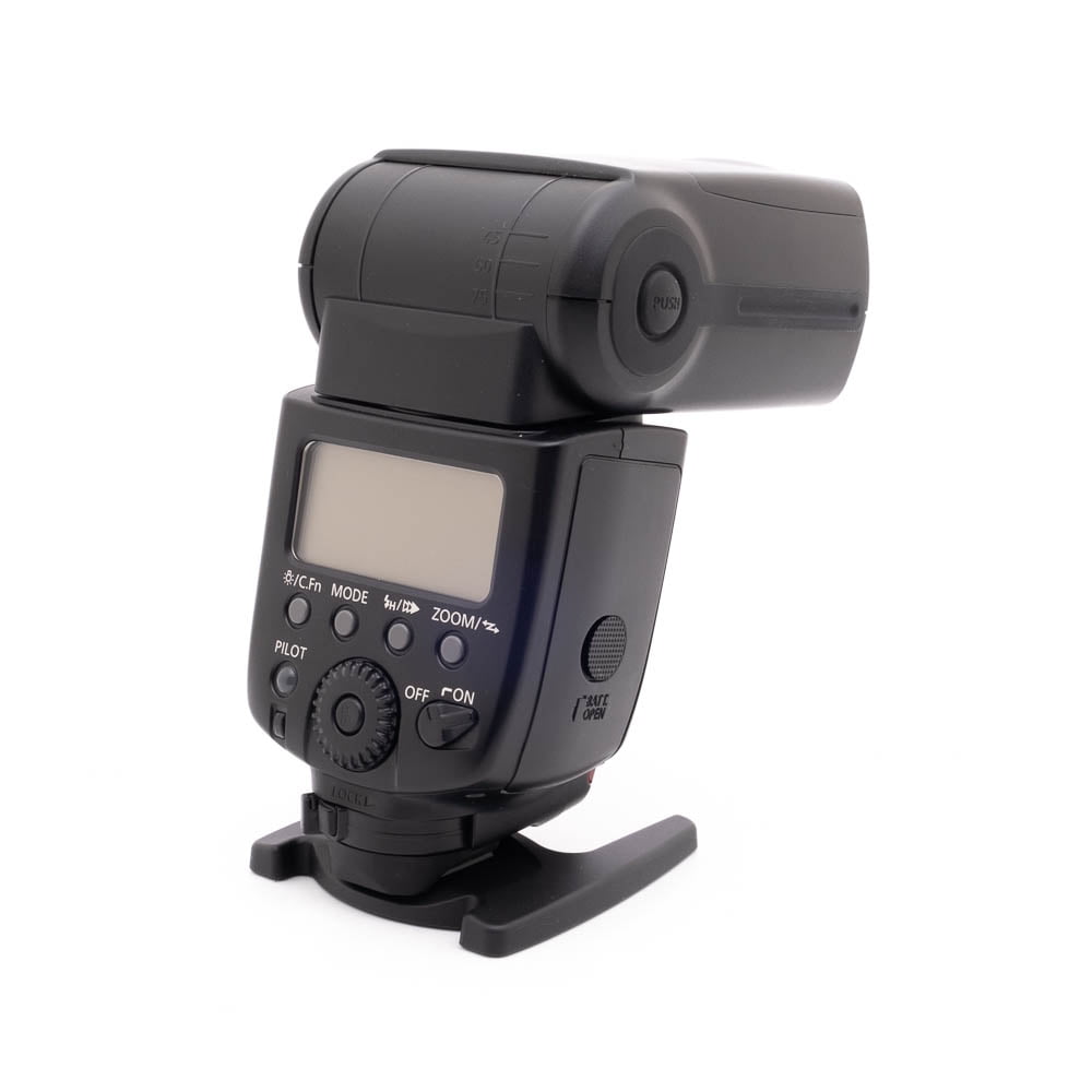 Canon Speedlite 580EX II-2-2 Käytetty Canon 580EX II Salama -kameran ulkoinen salama, jossa on digitaalinen näyttö ja ohjauspainikkeet, on asennettu pieneen jalustaan ja näytetään valkoista taustaa vasten.