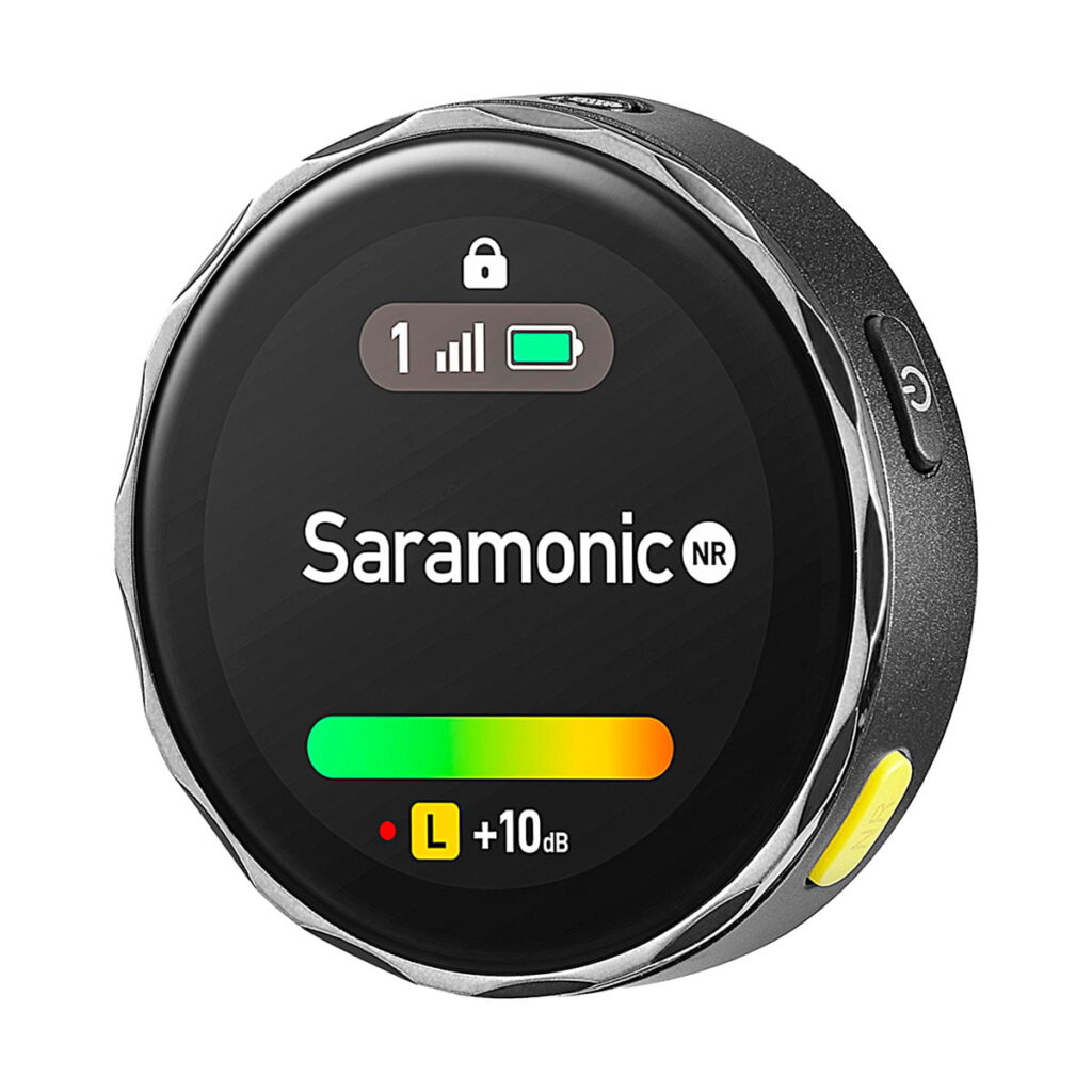 Saramonic_Blink_ME_B2_010 Lähikuva pyöreästä Saramonic BlinkMe B2 -langaton mikrofonijärjestelmä-lähettimestä, jossa on digitaalinen näyttö, jossa näkyy signaalin voimakkuus, akku ja äänenvoimakkuus sekä mustat, hopeiset ja keltaiset painikkeet.