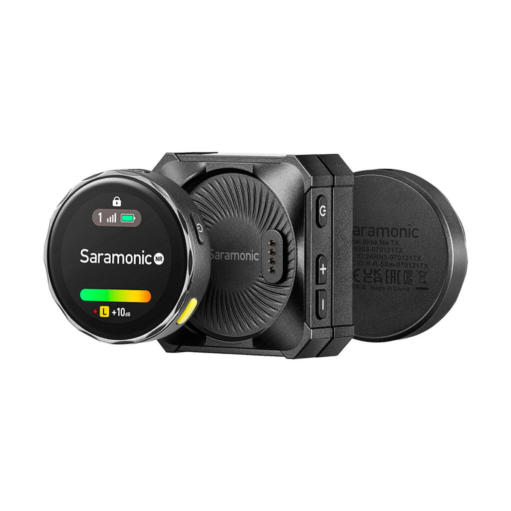 Saramonic_Blink_ME_B2_011 Saramonic BlinkMe B2 -langaton mikrofonijärjestelmä on kompakti musta langaton mikrofonijärjestelmä, jossa on signaalin ja akun pyöreä näyttö, joka on kiinnitetty suorakulmaiseen vastaanottimeen, jossa on painikkeet ja Saramonicin tuotemerkki.