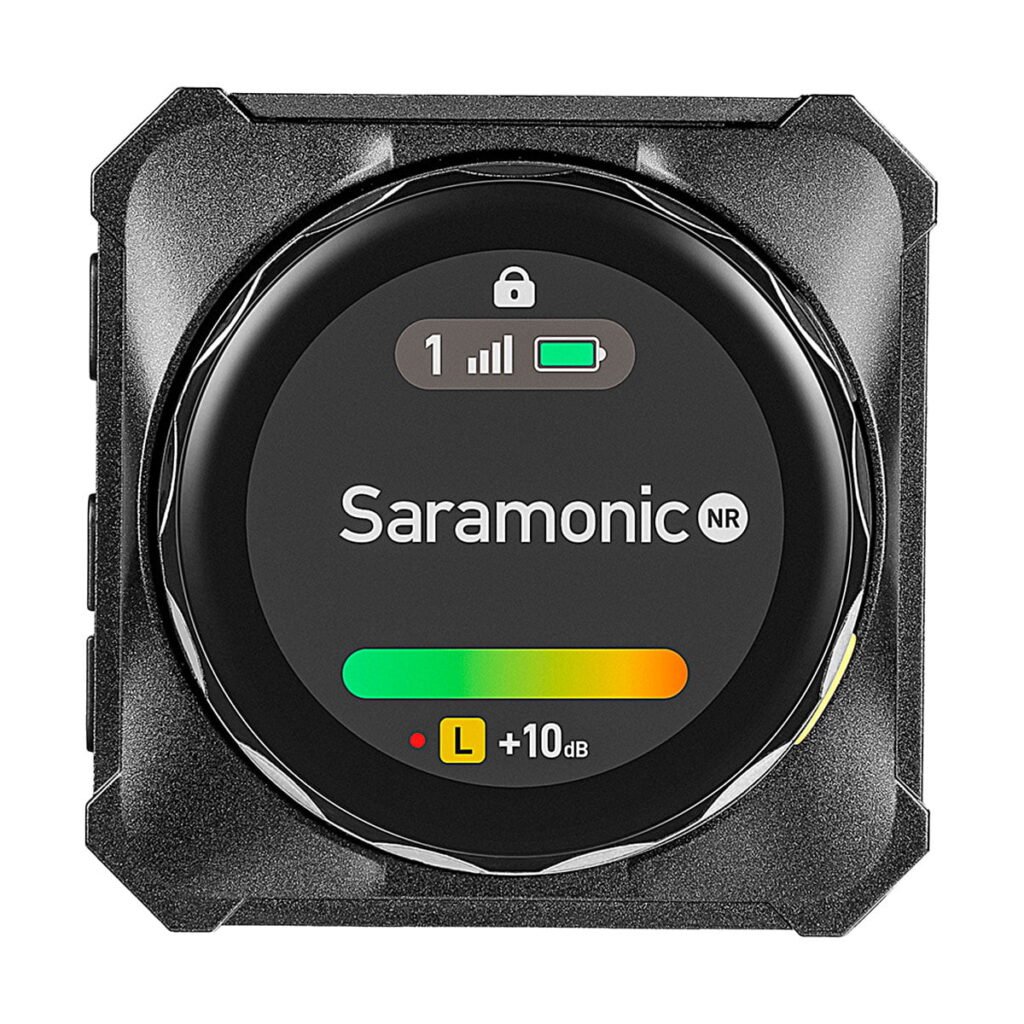 Saramonic_Blink_ME_B2_014 Lähikuva Saramonic BlinkMe B2 -langaton mikrofonijärjestelmä-lähettimestä, jossa on digitaalinen näyttö, jossa näkyy signaalin voimakkuus, pariston tila, lukituskuvake ja +10 dB:n äänitasomittari, jossa on vihreä ja keltainen palkki.