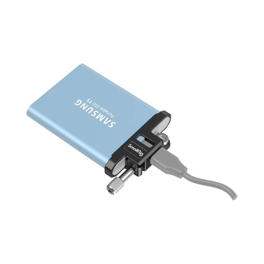 smallrig_3300_03 SmallRig 3300 Cable Clamp T5 SSD for BMPCC 6K PRO pitää sinistä Samsung Portable SSD T5 -levyä, joka on liitetty harmaalla kaapelilla pieneen mustaan ORICO-sovittimeen.