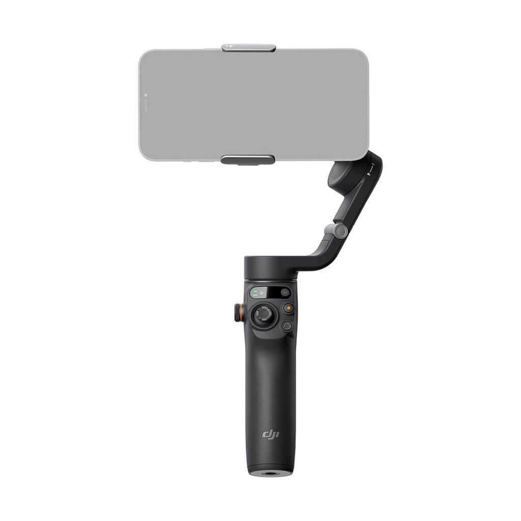 DJI_Osmo_Mobile_6_001 Älypuhelin istuu mustalla DJI Osmo Mobile 6 -gimbaali kännykälle -käsivakain vakaajalla valkoista taustaa vasten. Kahvassa on näkyvissä useita ohjauspainikkeita.