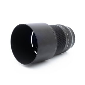 Fujinon 60mm f24 R Macro-3 Fujino's 60mm f/2.4 R Macro - Used lens, with its large lens hood and textured focus and zoom rings, lies on its side against a white background.
