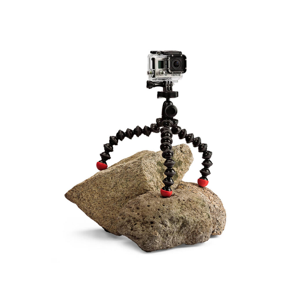 JOBY GorillaPod Action4 JOBY GorillaPod Action GoPro Jalusta, jossa on punaiset jalat, pitää GoPro-kameraa kahdella epätasaisella kivellä valkoista taustaa vasten.