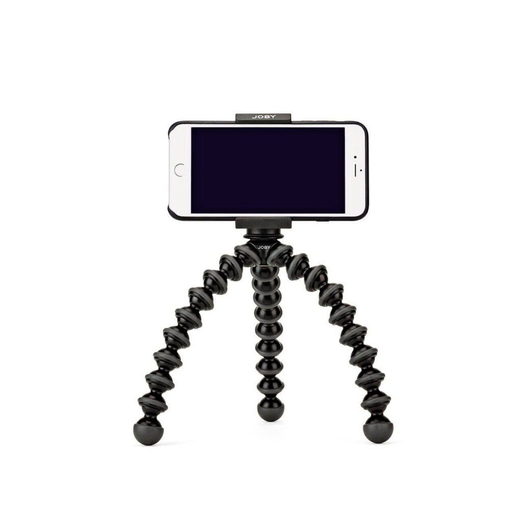 JOBY GripTight GorillaPod Stand PRO4 JOBY GripTight GorillaPod Stand PRO Jalusta Puhelimelle, musta taipuisa kolmella segmentoidulla taipuisalla jalalla varustettu kolmijalkainen jalusta, pitää älypuhelinta pystyssä valkoista taustaa vasten.