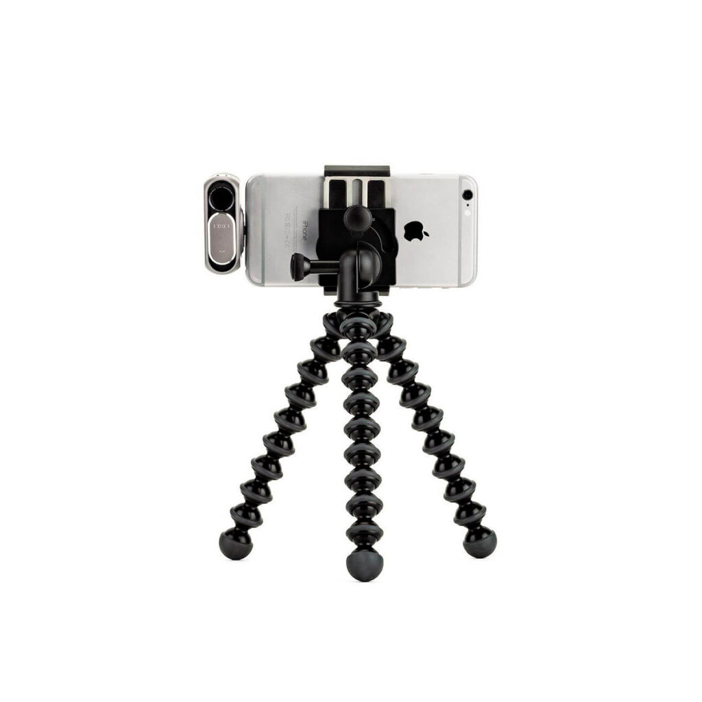 JOBY GripTight GorillaPod Stand PRO5 JOBY GripTight GorillaPod Stand PRO Jalusta Puhelimelle kiinnitetään älypuhelin, jossa on kiinnitettävä linssi, sen kolmelle joustavalle jalalle valkoista taustaa vasten.