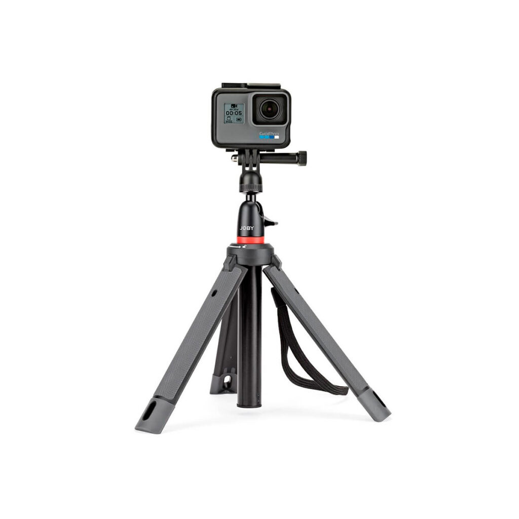 JOBY Telepod 325 Jalustakit6 GoPro-toimintakamera, joka on asennettu JOBY Telepod 325 Jalustakit Musta/Harmaa kompaktin mustaan jalustaan, jossa on säädettävät jalat ja rannehihna, valkoista taustaa vasten.