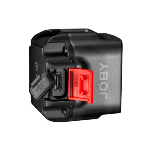 Pienikokoinen musta Joby Beamo - LED-valo, jossa on JOBY-logo, punainen salpa ja avoin kumikansi, joka paljastaa sivussa olevan USB-C-portin. Tausta on valkoinen.