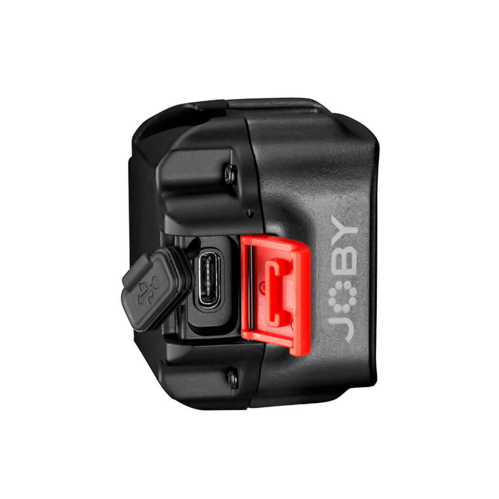 Joby Beamo Mini - LED-valo on musta laite, jossa on näkyvä USB-C-portti, kuminen porttisuojus ja näkyvä punainen salpa sivussa valkoista taustaa vasten.