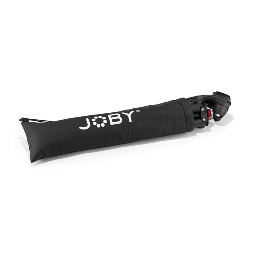 Joby-Compact-Action-3K-3 Joby-merkkisessä mustassa kantolaukussa on Joby Compact Action 3K -jalusta, joka on osittain näkyvissä vetoketjullisesta päädystä ulosvedettynä.