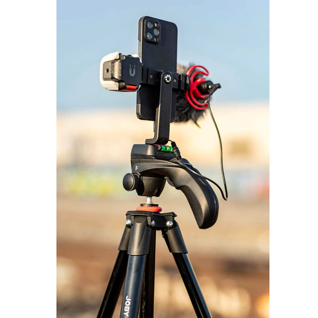 Joby-Compact-Action-3K-6 Joby Compact Action 3K -jalusta pitää ulkona mikrofonilla ja LED-valolla varustetun älypuhelimen valmiina videokuvausta tai vloggausta varten.