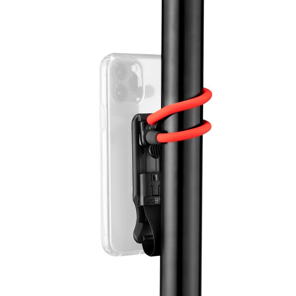 Joby-FreeHold-Universal-Kit-6 Läpinäkyvässä kotelossa oleva älypuhelin on kiinnitetty pystysuoraan mustaan tolppaan Joby FreeHold Universal Kitillä, jossa on musta kiinnitin ja punainen joustava nauha.