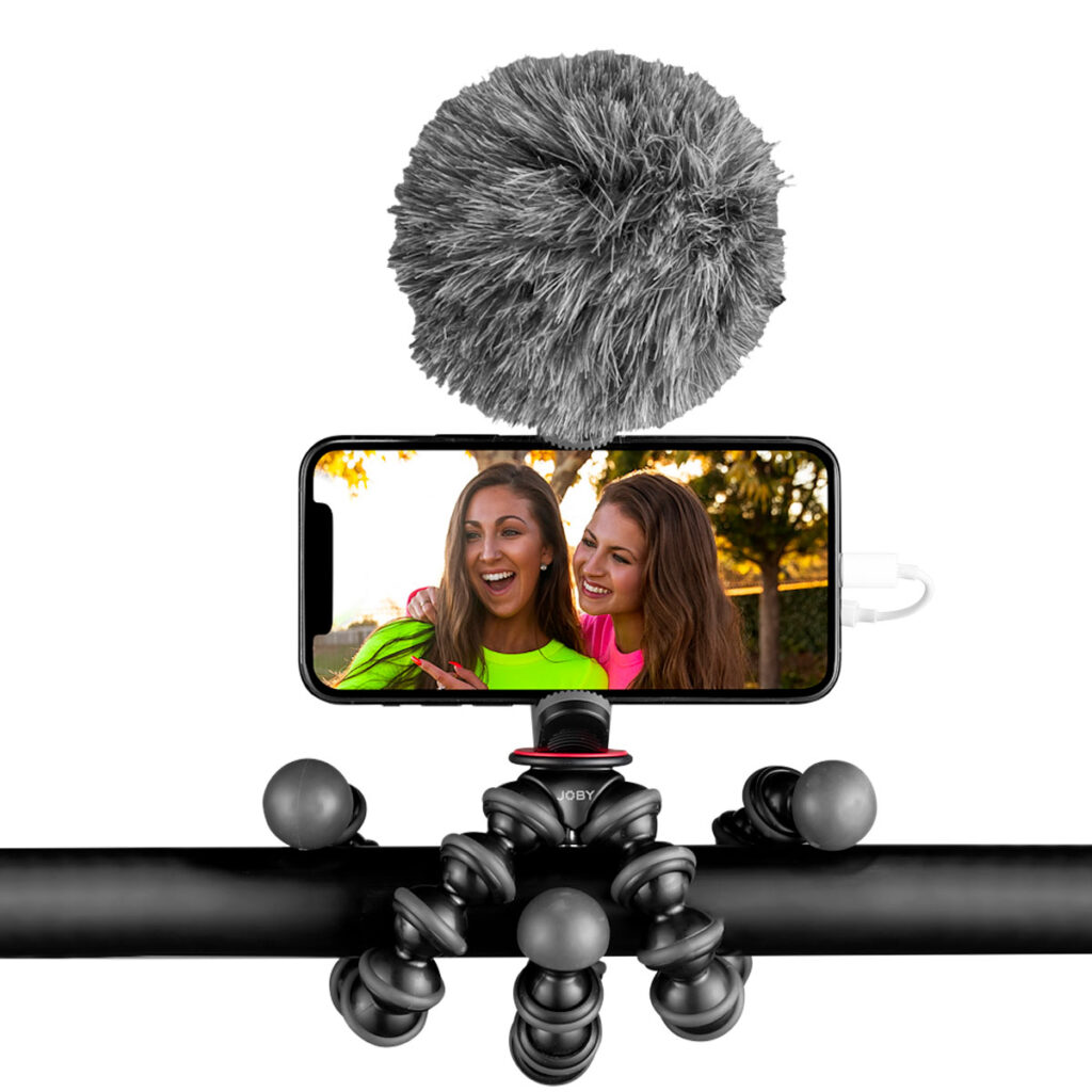 Joby-GorillaPod-Creator-Kit-4 Joby GorillaPod Creator Kit pitää älypuhelinta, jossa on karvainen mikrofoni, ja tallentaa kaksi hymyilevää naista kirkkaissa vaatteissa ulkona.