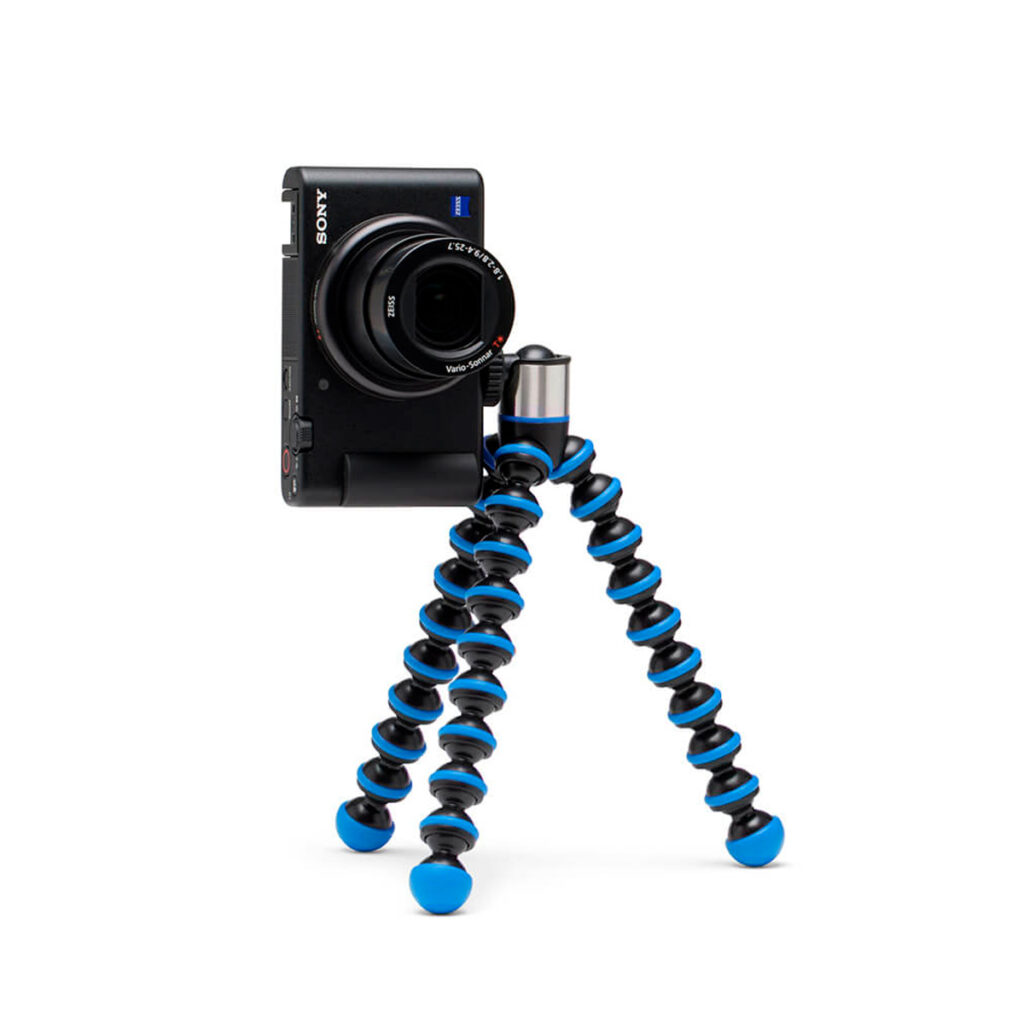 Joby-GorillaPod-Go-500-+-GripTight-360-Tripod-Kit-Blue-3 Kompakti Sony-kamera on kiinnitetty Joby GorillaPod Go 500 + GripTight 360 Tripod Kit Blue -jalustaan, jossa on mustat ja siniset segmentoidut jalat ja joka seisoo pystyssä valkoisella taustalla.