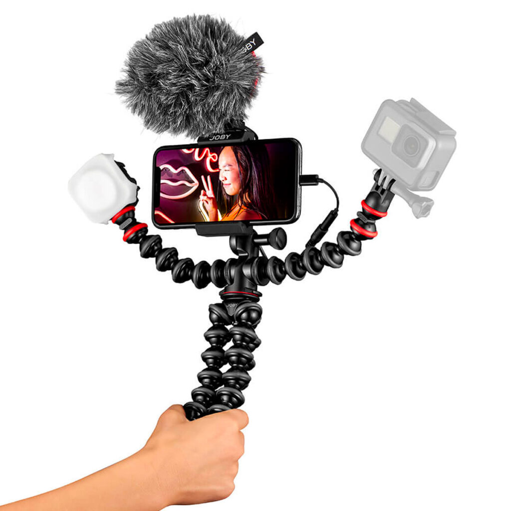 Joby-GorillaPod-Mobile-Vlogging-Kit-2 Kädessä on Joby GorillaPod Mobile Vlogging Kit, jossa on joustava kolmijalka, älypuhelimen kiinnike, mikrofoni, jossa on karvainen tuulisuoja, LED-valo ja toimintakamera - täydellinen mobiiliin videokuvaukseen tai vloggaamiseen.