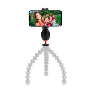 Joby-GripTight-Pro-3-2 Joby GripTight Pro 3 Phone Mount -puhelinkiinnike, jossa on valkoiset segmentoidut jalat, pitää älypuhelimen tukevasti vaakasuorassa ja näyttää hymyilevien ihmisten ryhmäselfien ulkona aurinkoisessa, vihreässä ympäristössä.