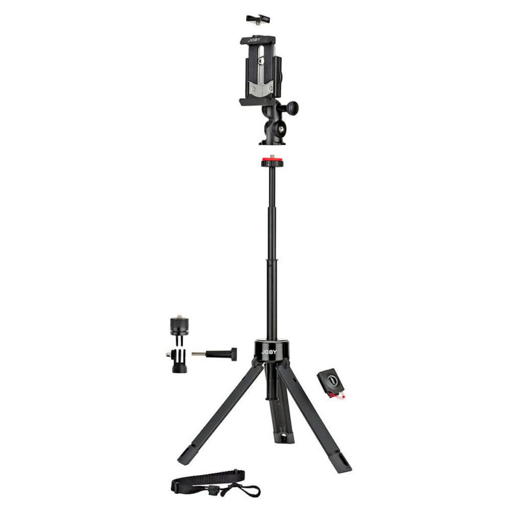 Joby-GripTight-Pro-TelePod-2 Joby GripTight Pro TelePod on musta, ulosvedettävä kolmijalka, jonka päällä on älypuhelimen pidike. Kuvassa on lisävarusteita, kuten Bluetooth-kaukosäädin, kiinnike ja hihna sen ympärillä, ja sen jalat ovat pidennetyt vakauden lisäämiseksi.