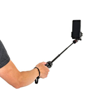 Joby-GripTight-Pro-TelePod-5 Henkilö pitää Joby GripTight Pro TelePod -jalustaa, johon on kiinnitetty älypuhelin, valkoista taustaa vasten. Vain hänen kätensä ja osa vartalosta ovat näkyvissä.