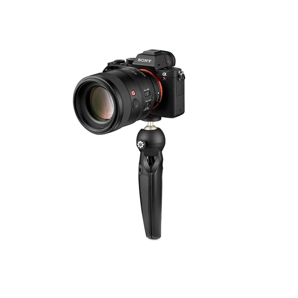 Joby HandyPod4 Musta Sony Alpha -peilitön kamera, jossa on suuri objektiivi, on asennettu JOBY HandyPod Jalusta Musta -jalustalle valkoista taustaa vasten.