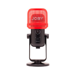 Joby-Microphone-Wavo-POD Joby Wavo POD -mikrofoni on musta pöytämikrofoni, jossa on JOBY-logolla varustettu punainen verkkomallinen pop-suodatin, joka on asennettu pyöreään jalustaan valkoista taustaa vasten.