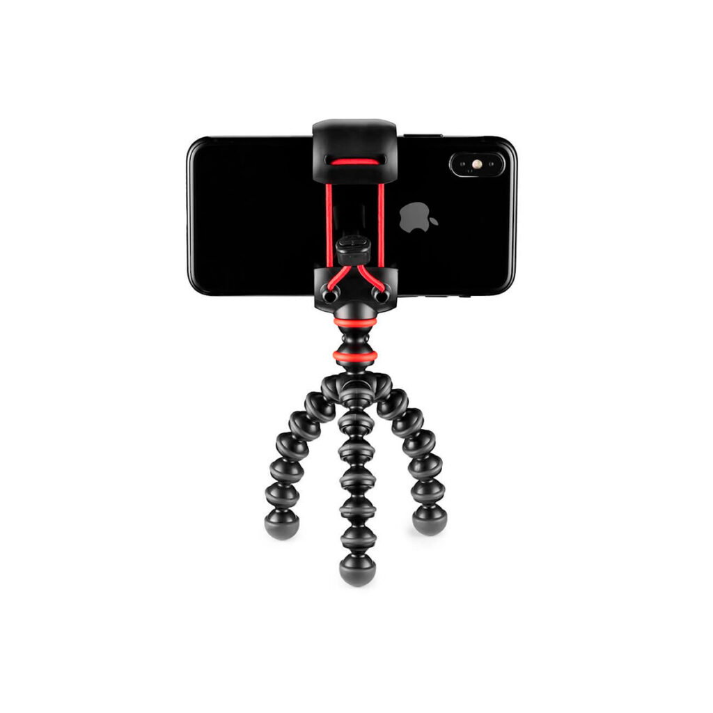 Joby Starter Kit GorillaPod8 JOBY GorillaPod Starter Kit, musta ja punainen, pitää älypuhelinta vaakasuorassa niin, että Applen logo ja kamera ovat näkyvissä. Jalusta seisoo valkoisella taustalla.