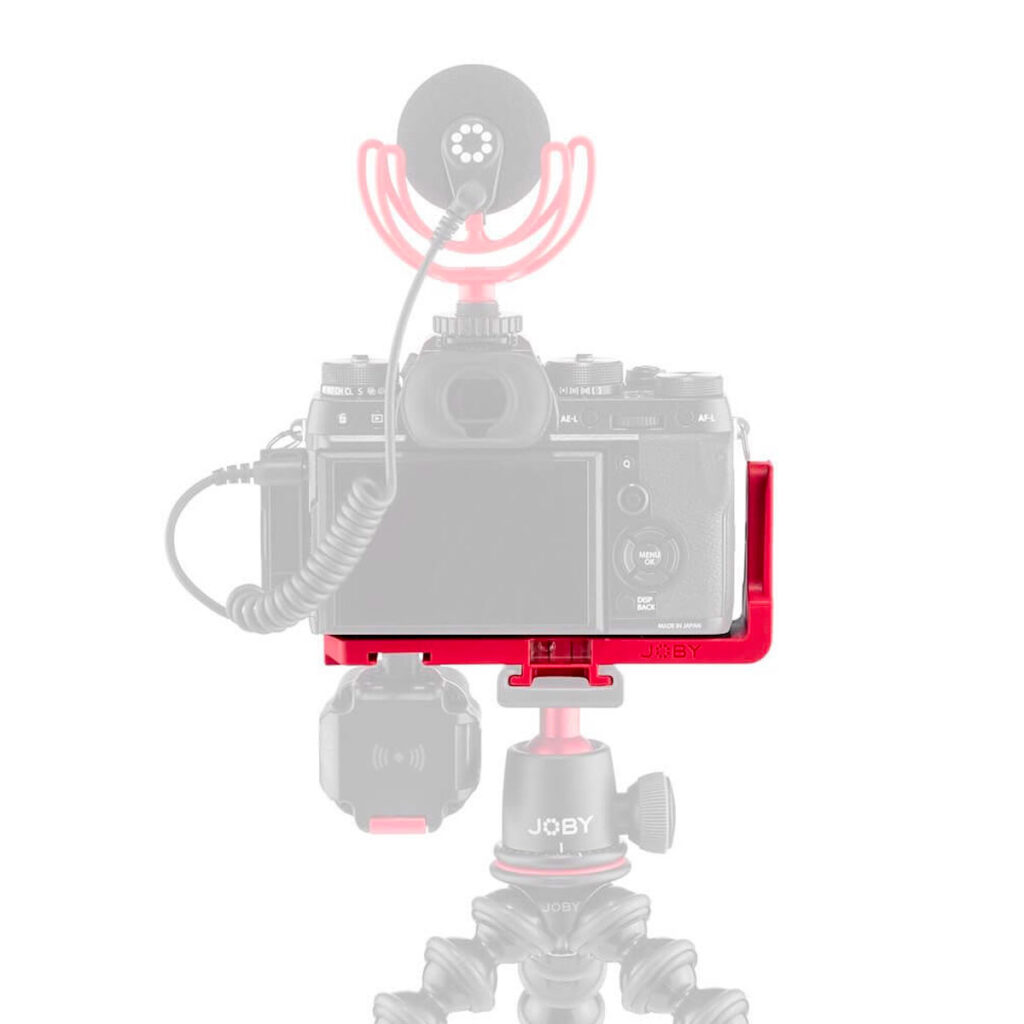 Joby-Vert-Vertical-L-Bracket-6 The red cage-mounted digital camera with external microphone sits on the Joby Vertical L Bracket, which is attached to a flexible stand. The camera and accessories appear in a semi-transparent style.