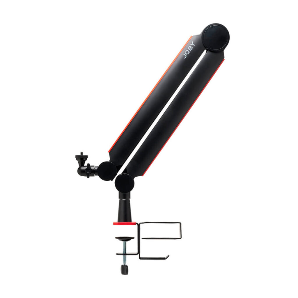 Joby-Wavo-Boom-Arm-2 Joby Wavo Boom Arm on mustan ja punaisen värinen säädettävä mikrofonivarsijalusta, jossa on pöytäkiinnike, kuvassa sivukuva valkoista taustaa vasten.