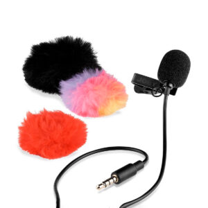 Joby-Wavo-Lav-Mikrofoni Joby Wavo Lav Mikrofoni, musta clip-on lavalier-mikrofoni, jossa on vaahtomuovinen tuulisuoja ja 3,5 mm:n liitin, on esillä kolmen karvaisen tuulisuojan vieressä: musta, punainen ja monivärinen sekoitus vaaleanpunaista, keltaista ja violettia.