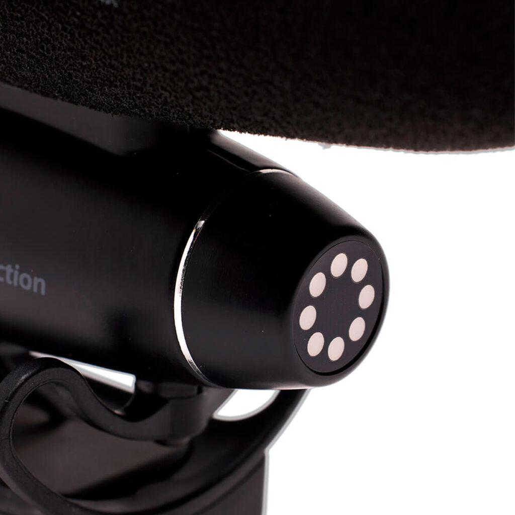 Joby-Wavo-Pro-4 Lähikuva Joby Wavo Pro - Mikrofonin mustasta, pyöreästä päästä, jossa on kahdeksan valkoista pyöreää merkintää, jotka on asetettu rullalautakannen pitoteippiä muistuttavan teksturoidun pinnan alle.