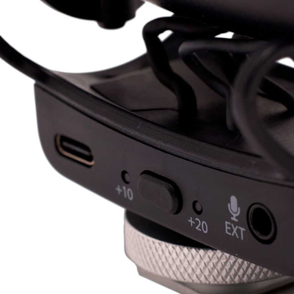 Joby-Wavo-Pro-5 Joby Wavo Pro - Mikrofoni -kuulokkeen lähikuvasta paljastuu USB-C-portti, kytkin +10- ja +20-asetuksilla, EXT-tulon merkkivalo, jossa on mikrofonikuvake, sekä selkeät mustat ja hopeiset komponentit.
