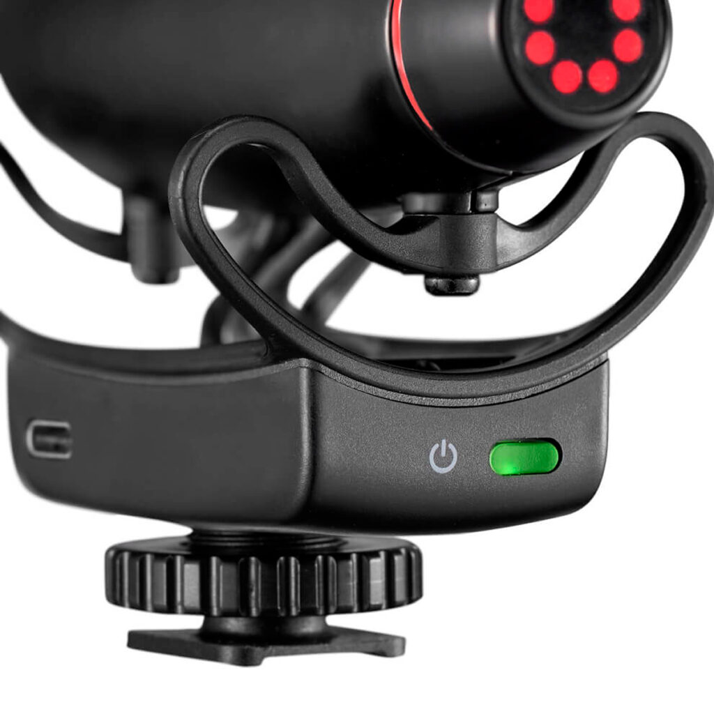 Joby-Wavo-Pro-DS-3 Lähikuva Joby Wavo Pro DS - Mikrofoni mustana, jossa on iskukiinnike, vihreä virran merkkivalo, USB-C-portti sivulla ja kiinnitysruuvi pohjassa jalustaa tai kameran kiinnitystä varten.