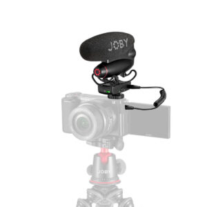Joby-Wavo-Pro-DS-5 Pienikokoinen kamera, jossa on ulos käännettävä näyttö, on kiinnitetty Joby-jalustalle. Joby Wavo Pro DS - Mikrofoni on kiinnitetty kameran kuumakenkään kierrekaapelilla. Asetelma näkyy valkoista taustaa vasten.