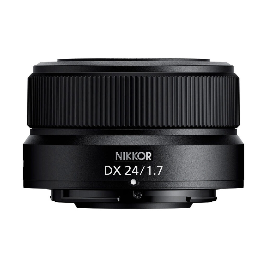 Nikon_Nikkor_Z_DX_24mm_f_1_7_002 Lähikuva mustasta Nikon Nikkor Z DX 24mm f/1.7 -objektiivista, jonka sivulla on valkoinen malliteksti, valkoista taustaa vasten.