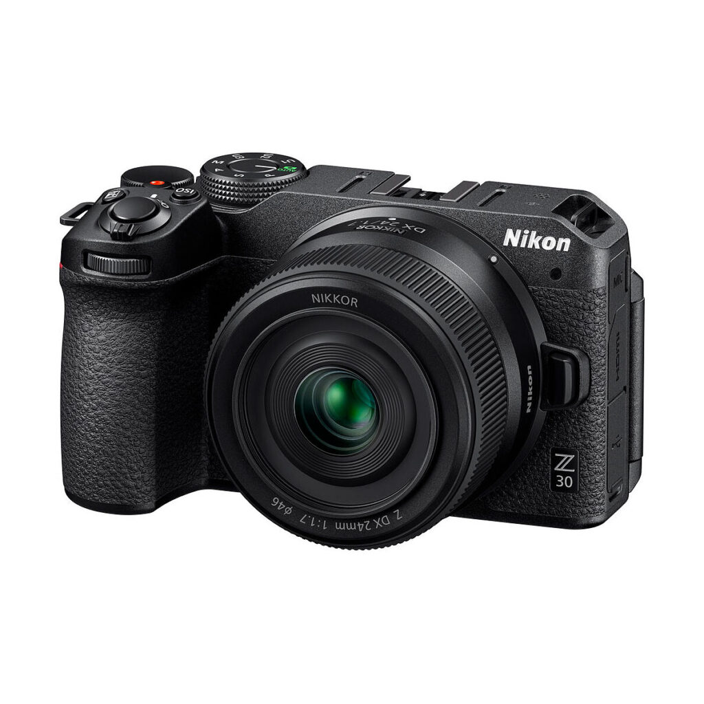 Nikon_Nikkor_Z_DX_24mm_f_1_7_004 Musta Nikon Z30 -peilitön kamera, jossa on NIKKOR Z DX 24mm f/1.7 -objektiivi, näkyy edestä, ja siinä korostuvat ylä- ja sivupainikkeet ja valitsimet.