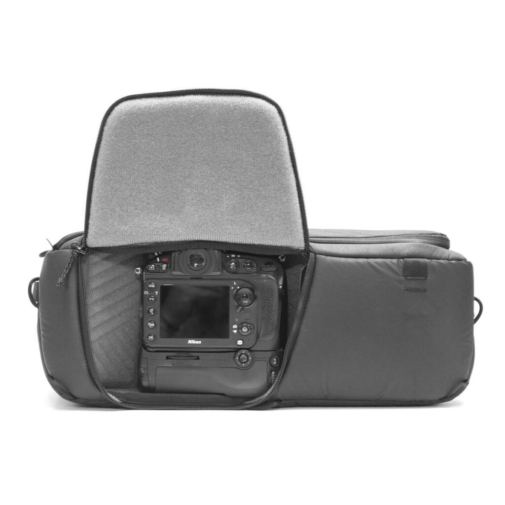 Peak-Design-Camera-Cube-medium5 Peak Design Camera Cube Medium -kamerakuutio näytetään avattuna, ja sen pehmustetun lokeron sisältä paljastuu ammattikäyttöön tarkoitettu DSLR-kamera, jonka näyttö ja ohjauspainikkeet ovat näkyvissä.