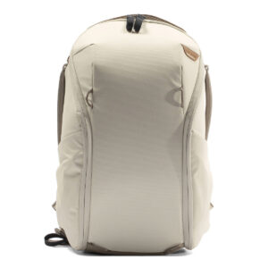 Peak-Design-Everyday-Backpack-Zip-15L-bone-2 Peak Design Everyday Backpack Zip 15L -kamerareppu Bone on pystyssä valkoista taustaa vasten, ja siinä on minimalistinen beige muotoilu, sivutaskut, yläkahva ja ruskeat koristeet.