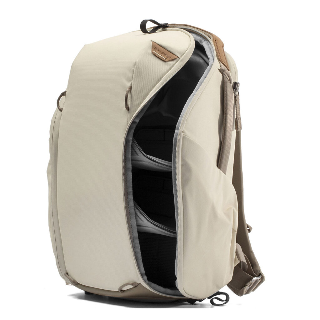 Peak-Design-Everyday-Backpack-Zip-15L-bone-4 Peak Design Everyday Backpack Zip 15L -kamerareppu, Bone, on beige reppu, jossa on yläkahva ja pehmustetut olkahihnat. Siinä on sivuvetoketjullinen aukko kahteen pehmustettuun lokeroon järjestettyä säilytystä ja helppoa käyttöä varten.
