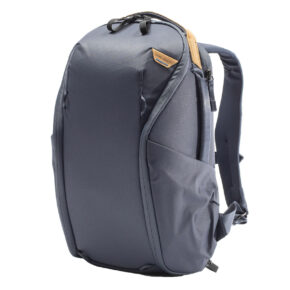 Peak-Design-Everyday-Backpack-Zip-15L-midnight-1 Peak Design Everyday Backpack Zip 15L Midnight on moderni, tummanharmaa reppu, jossa on tyylikäs muotoilu, pehmustetut olkahihnat, sivutaskut ja ruskehtava aksentti lähellä yläreunaa. Se seisoo pystyssä valkoista taustaa vasten.