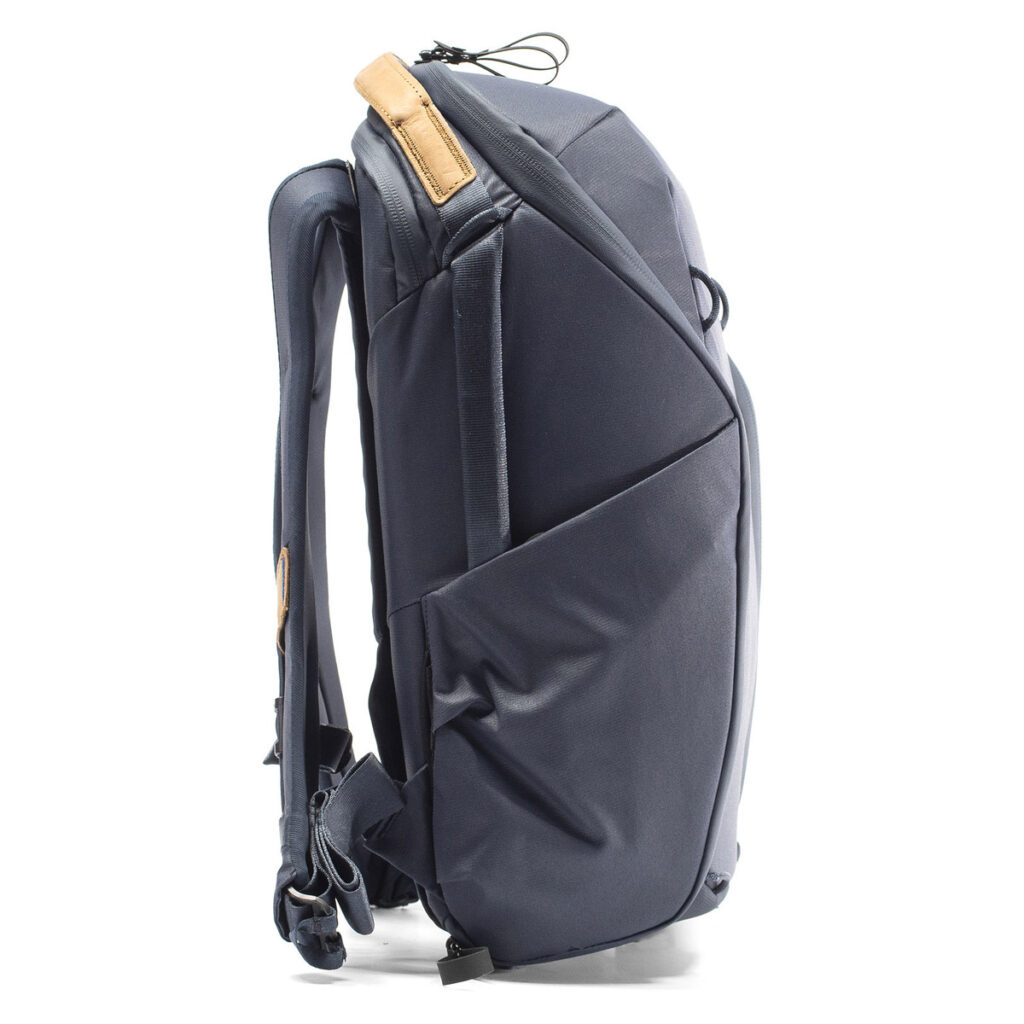 Peak-Design-Everyday-Backpack-Zip-15L-midnight-3 Sivunäkymä Peak Design Everyday Backpack Zip 15L Midnight -repusta, jossa on pehmustetut olkahihnat, ruskehtava nahkakahva ja sivutaskut, pystyasennossa valkoisella pohjalla.